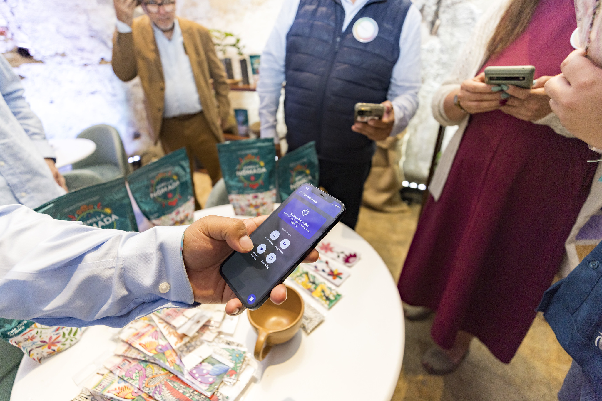 People tapping their phones near a vendor's table while making a purchase.